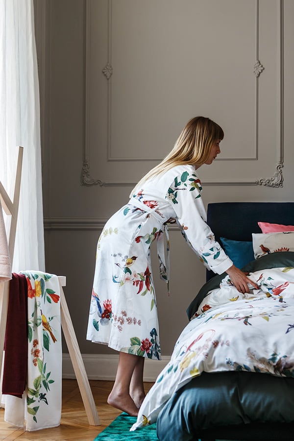 Blonde Frau in Bademantel von Gute N8! neben ihrem Bett